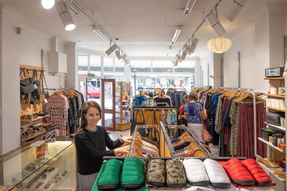 Inside the Wanda Harland store in Petone. It has a glass front with the sun shining in the store. Racks of clothing line the walls.