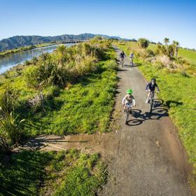 2 adults and 2 children bike alongside the Hutt River.