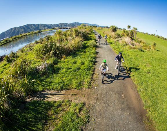 2 adults and 2 children bike alongside the Hutt River.