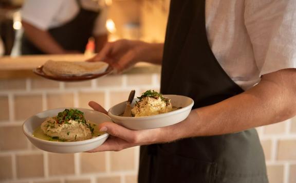 Close up of a waiters hands holding 3 plates of food.