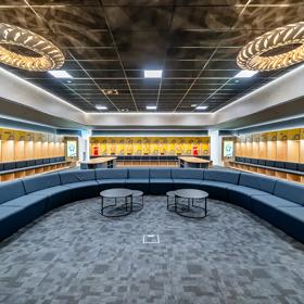 Changing rooms at NZCIS with lockers on three walls of the room, large ceiling lights and blue couches in a large U-shape layout.