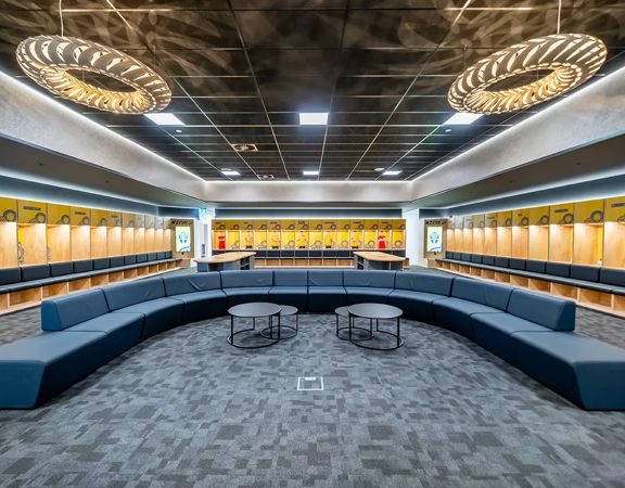 Changing rooms at NZCIS with lockers on three walls of the room, large ceiling lights and blue couches in a large U-shape layout.