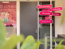 Inside the Strictly Savvy office, a virtual assistant company based in Upper Hutt. There is a hot pink way-finding post with their services listed. 