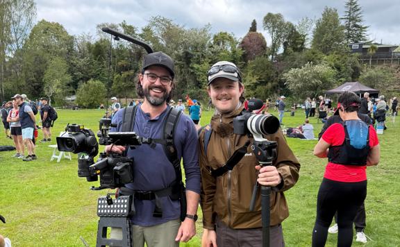 Two screen accelerator programme participants holding camera equipment in a field.