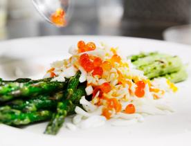 Close-up of dish containing grilled asparagus, cured salmon caviar, grated soft egg, capers and lemon mayo.
