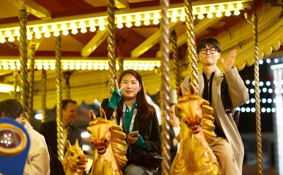 Two people ride on a merry-go-round. 
