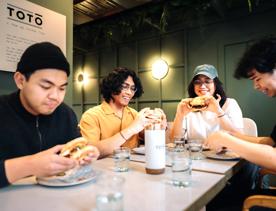 A group of four friends sit at a table enjoying burgers.