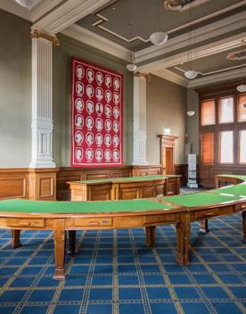 The Von Kohorn room in the Wellington Museum set up with a semi circle of green tables surrounding a large green desk.