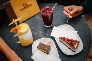 Two pieces of cake and two smoothies on a table.