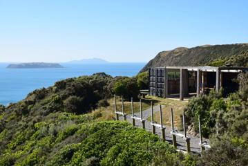 In the foreground is the shooting range and a building made from shipping container, wish bush surrounding. In the background is the view off the Kapati coast with Mana and Kapati Islands.