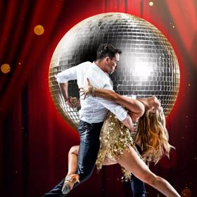 Two dancers are doing a romantic pose on a stage farmed with red curtains and a massive disco ball behind them.