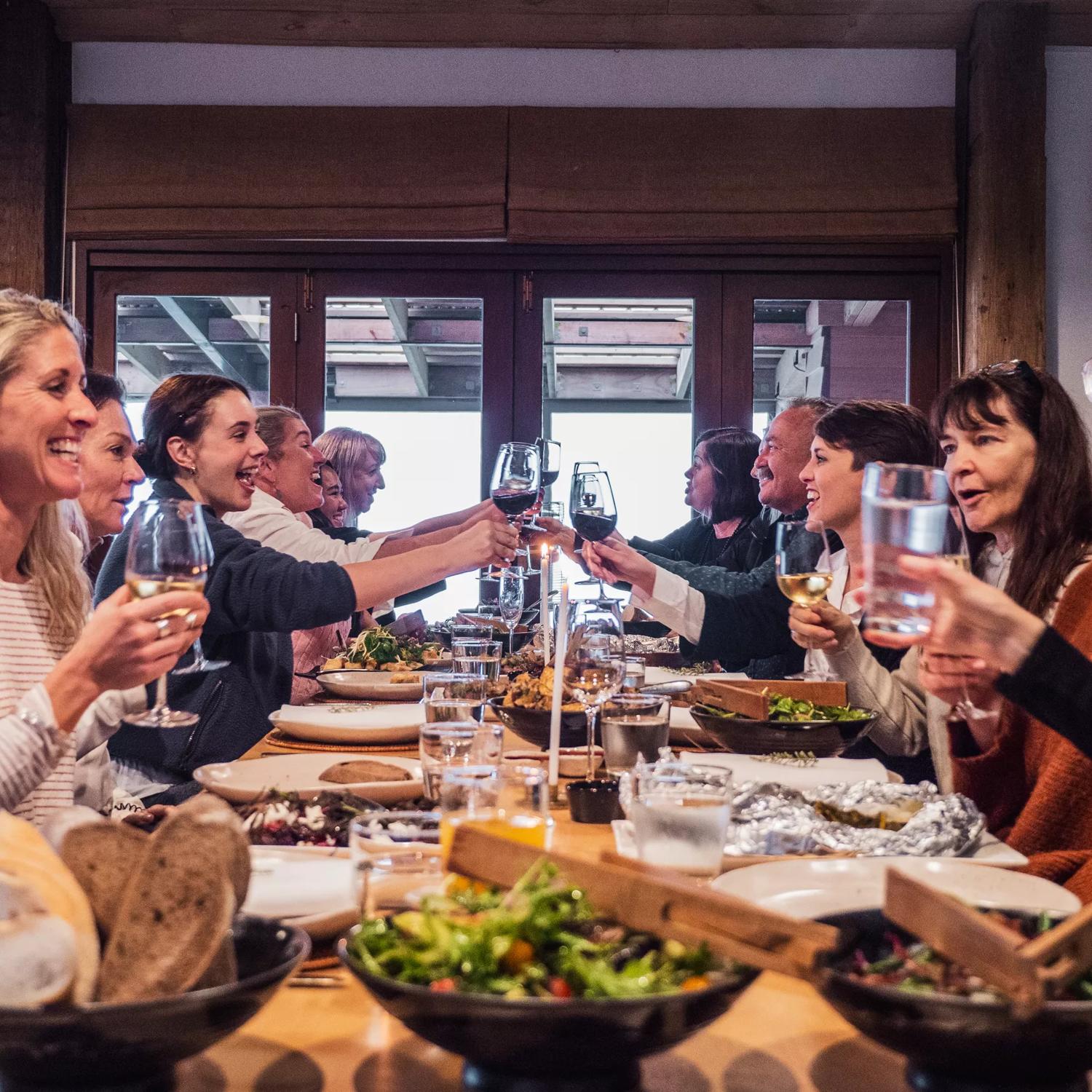 Ten people are enjoying a dinner together, clinking their wine glasses at Boomrock, a function and event venue located in Ohariu, Wellington.