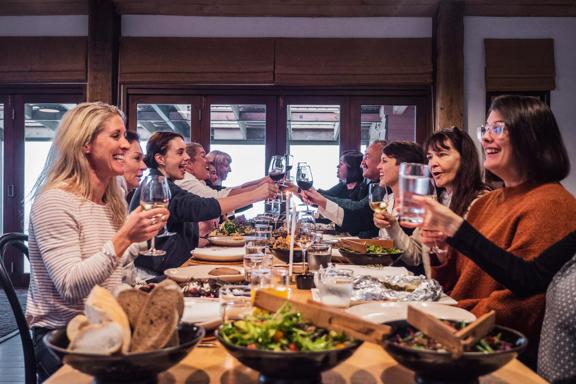 Ten people are enjoying a dinner together, clinking their wine glasses at Boomrock, a function and event venue located in Ohariu, Wellington.
