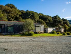 Camp Wainuiomata screen location. Has several buildings and is surrounded by forest and bush.