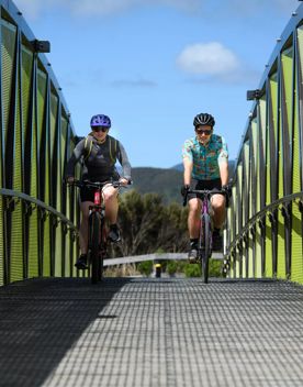 2 people on mountain bikes crossing a bridge on the Wainuiomata connector ride.