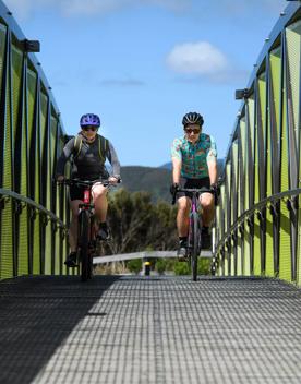 2 people on mountain bikes crossing a bridge on the Wainuiomata connector ride.