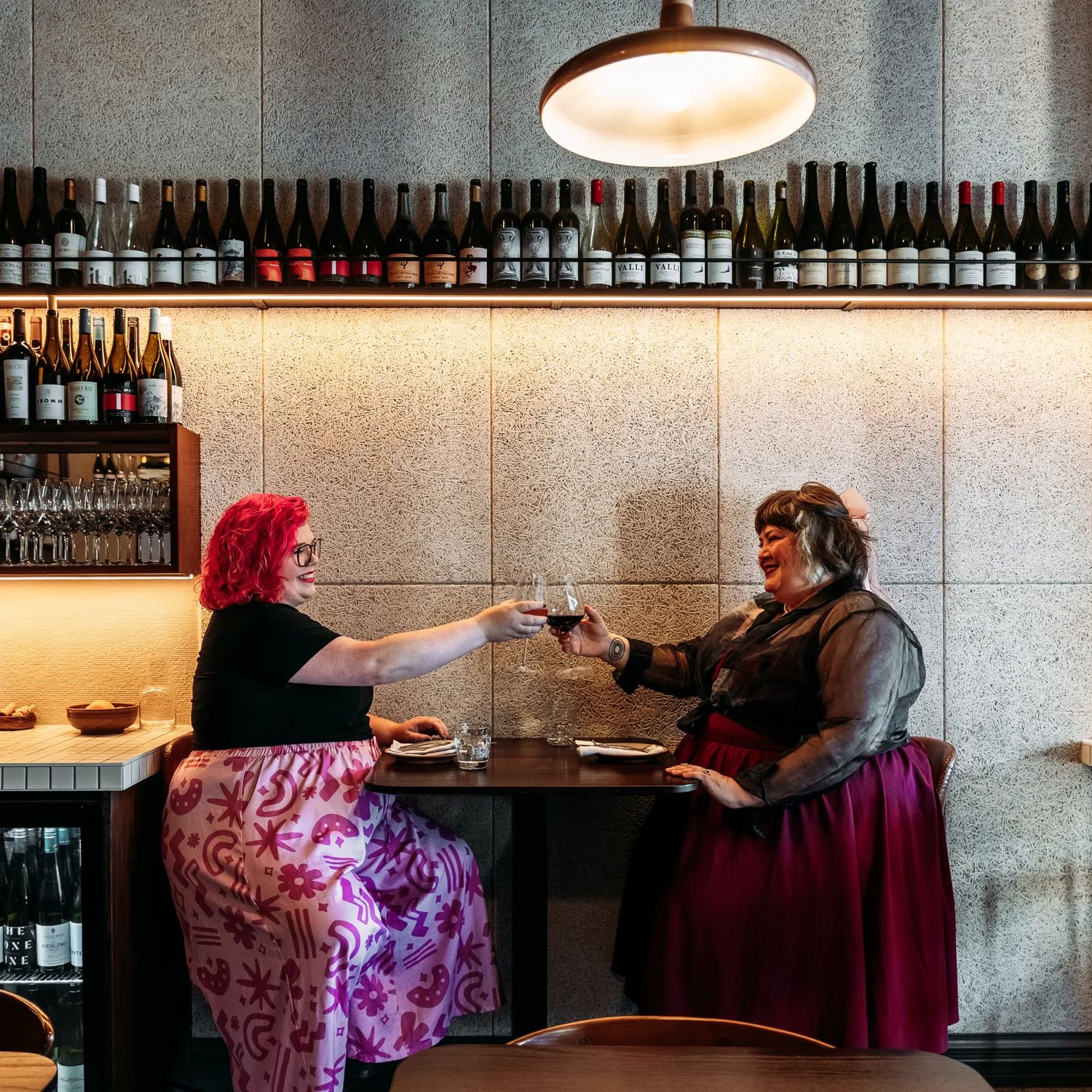 Two people toast with glasses of wine at Rosella.