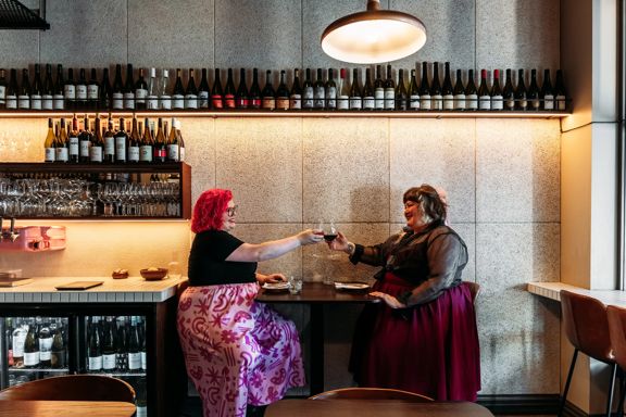Two people toast with glasses of wine at Rosella.