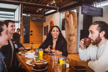 Four friends are having coffee and food at a café.