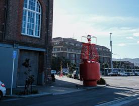 Bunny Street, Wellington. The brick railway building is in the distance, with another brick building in the foreground. A big red shipping bouy sits on the corner.