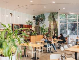 At Zealandia's Rātā Café, two groups of visitors sit at wooden tables inside the bright and spacious café.