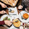Looking down at a table of food inside Hippo, QT Wellington. Customers use a knife and fork to grab food.