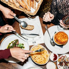 Looking down at a table of food inside Hippo, QT Wellington. Customers use a knife and fork to grab food.