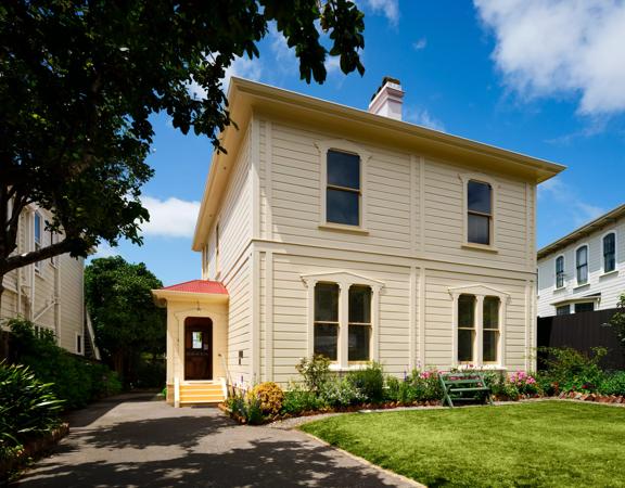 The yellow exterior of Katherin mainsfields house with a well kept garden.