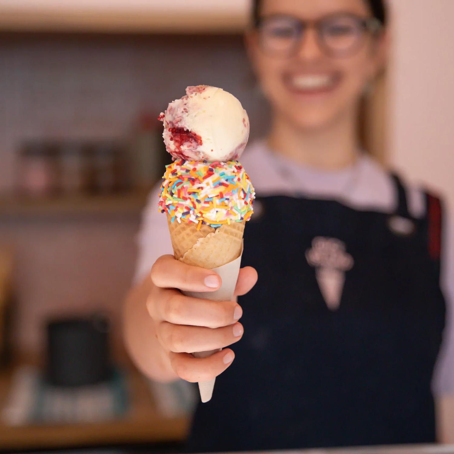 A staff member handing over an ice cream with sprinkles from Duck Island, Cuba Street.