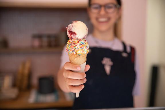 A staff member handing over an ice cream with sprinkles from Duck Island, Cuba Street.