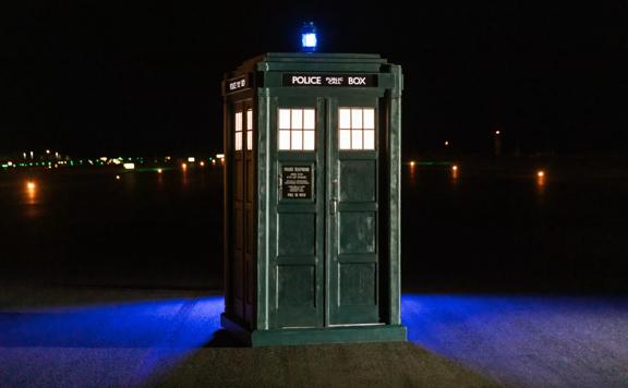 The 'TARDIS' blue police box was placed on the Wellington Airport runway in the dark. A blue light sits on top of the box illuminating the ground behind it.