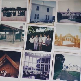 Vintage photographs of buildings, people, and landscapes arranged on a wooden surface.