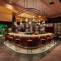 A swanky hotel bar with colourful art deco decor and low lighting.