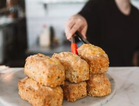 A person using tongs to place a cheese scone onto a stack on a marble plate at Floriditas, a restaurant on Cuba Street in Te Aro, Wellington.