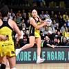 Netballer Whitney Souness of the Pulse jumps on the court with the netball in her hand. She wears the yellow and black team dress and the crowd is behind her.