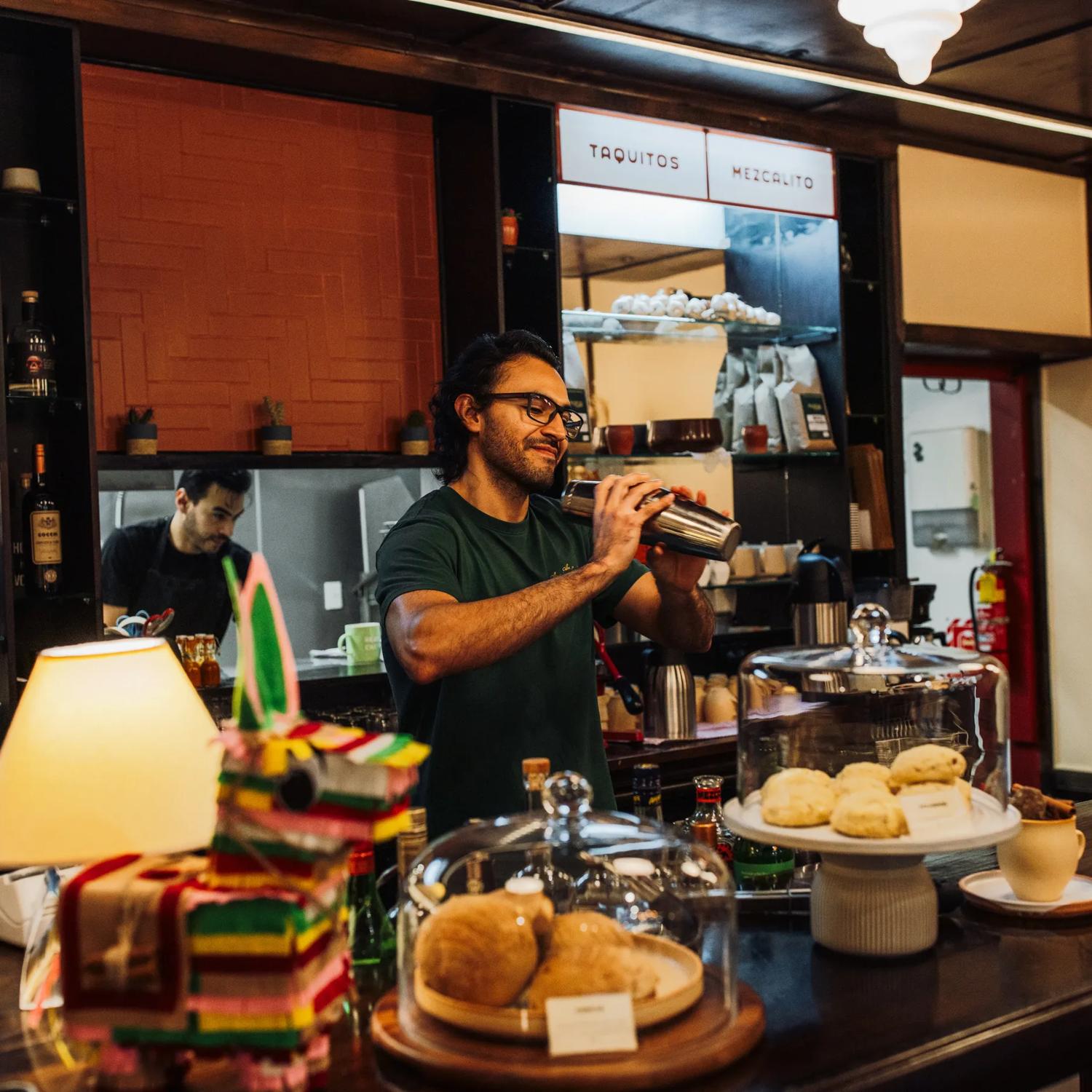 A bartender uses a cocktail shaker behind the counter at Apapachos in Wellington.
