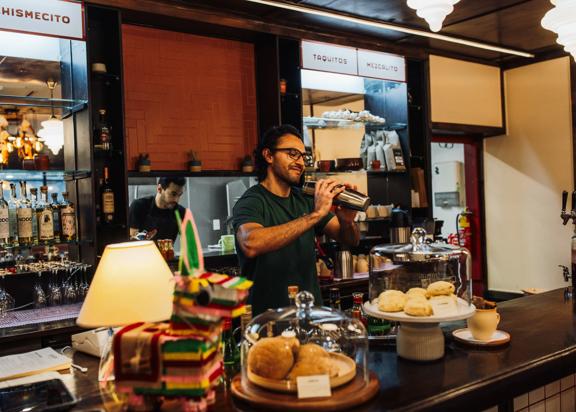 A bartender uses a cocktail shaker behind the counter at Apapachos in Wellington.