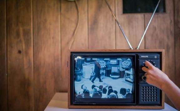 A hand playing with a very old TV showing black and white pictures, in Nairn Street cottage, Wellingtons oldest original cottage and heritage garden.