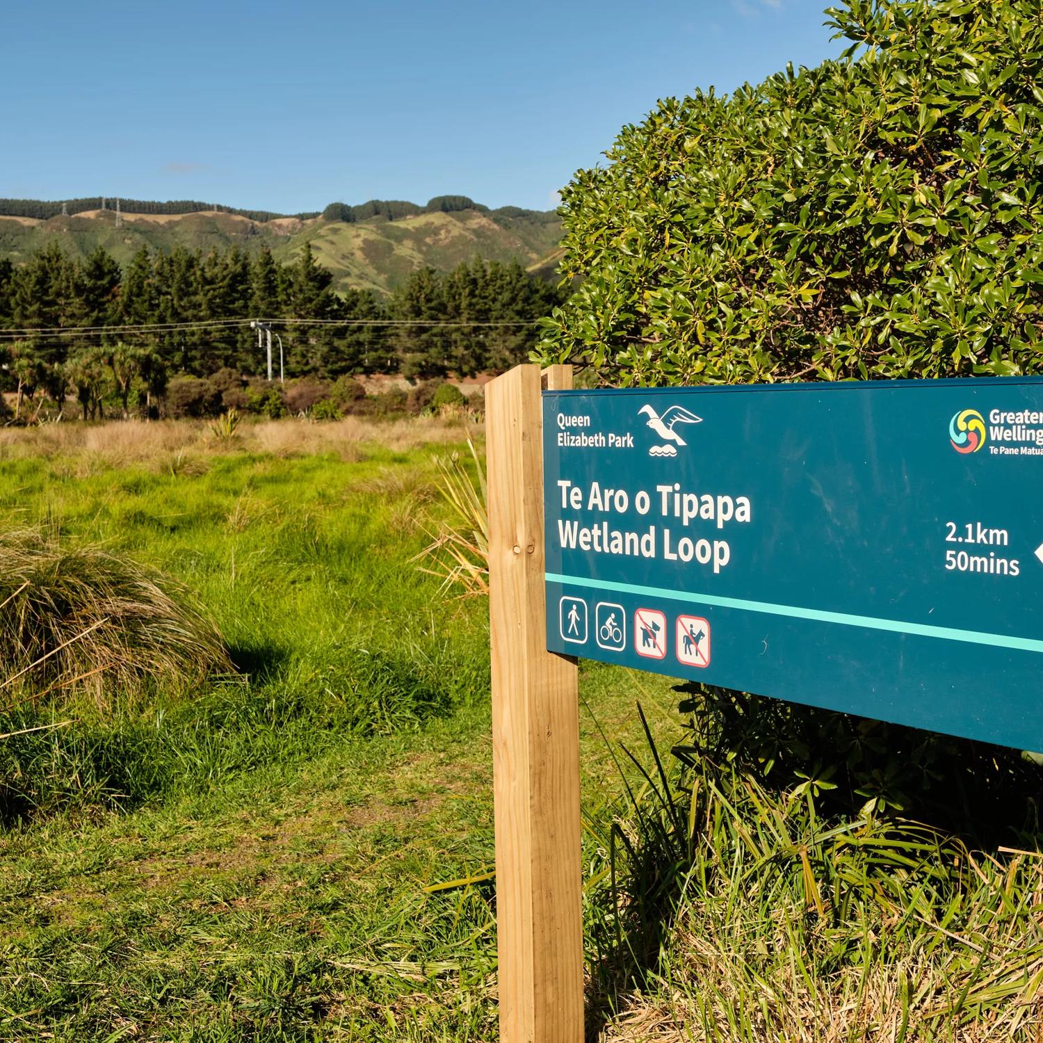 A sign post that reads 'Te Aro o Topapa Wetland Loop' in Queen Elizabeth Park.