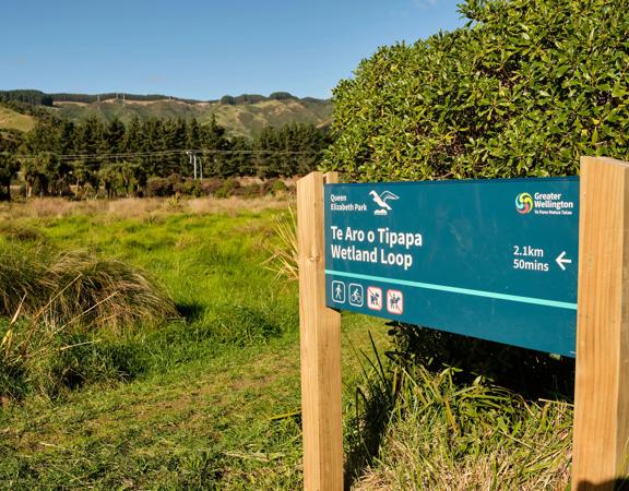 A sign post that reads 'Te Aro o Topapa Wetland Loop' in Queen Elizabeth Park.