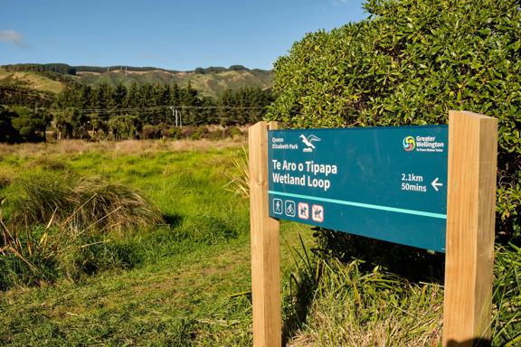 A sign post that reads 'Te Aro o Topapa Wetland Loop' in Queen Elizabeth Park.