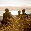 Four cyclists stop to rest by a bush in the early morning sunlight on Red Take Track at Whareroa Farm.