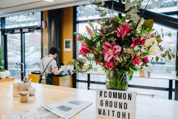 A large bouquet of pink and white lilies and roses on a table at Common Ground Café.