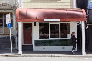 The exterior of Rosella, a turn of the century building with a red tin roof canopy over the verandah.