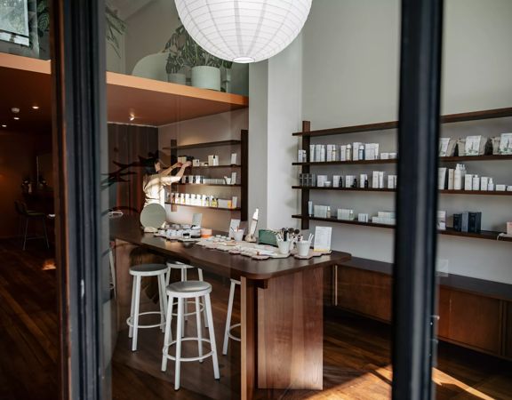 Looking into Iris Store + Studio adorned with their beauty products in white bottles on shelves along the wall and a counter in the centre.