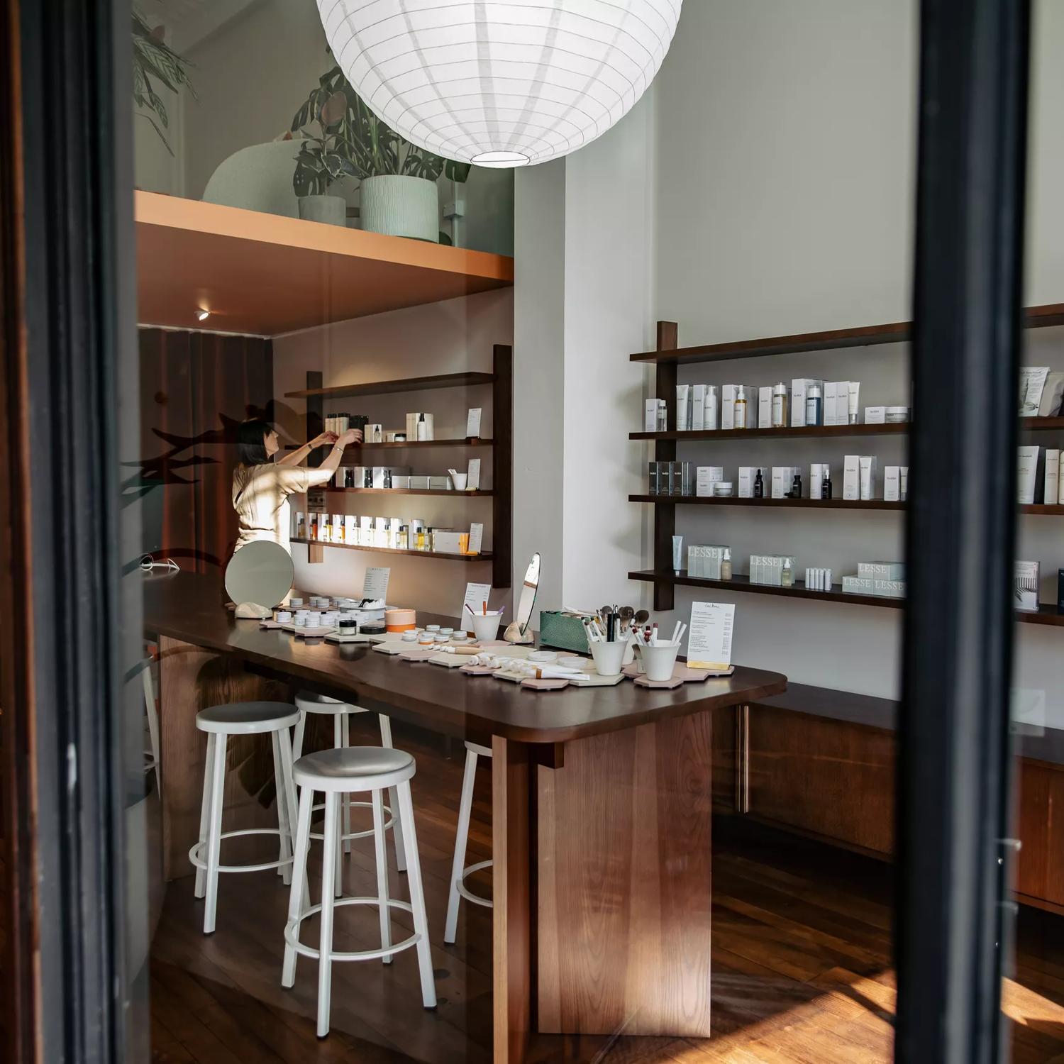 Looking into Iris Store + Studio adorned with their beauty products in white bottles on shelves along the wall and a counter in the centre.