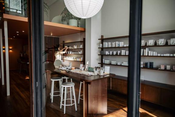 Looking into Iris Store + Studio adorned with their beauty products in white bottles on shelves along the wall and a counter in the centre.