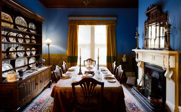 The dining room of Katherine Mansfields house with blue painted walls and a dinner setting on the table.