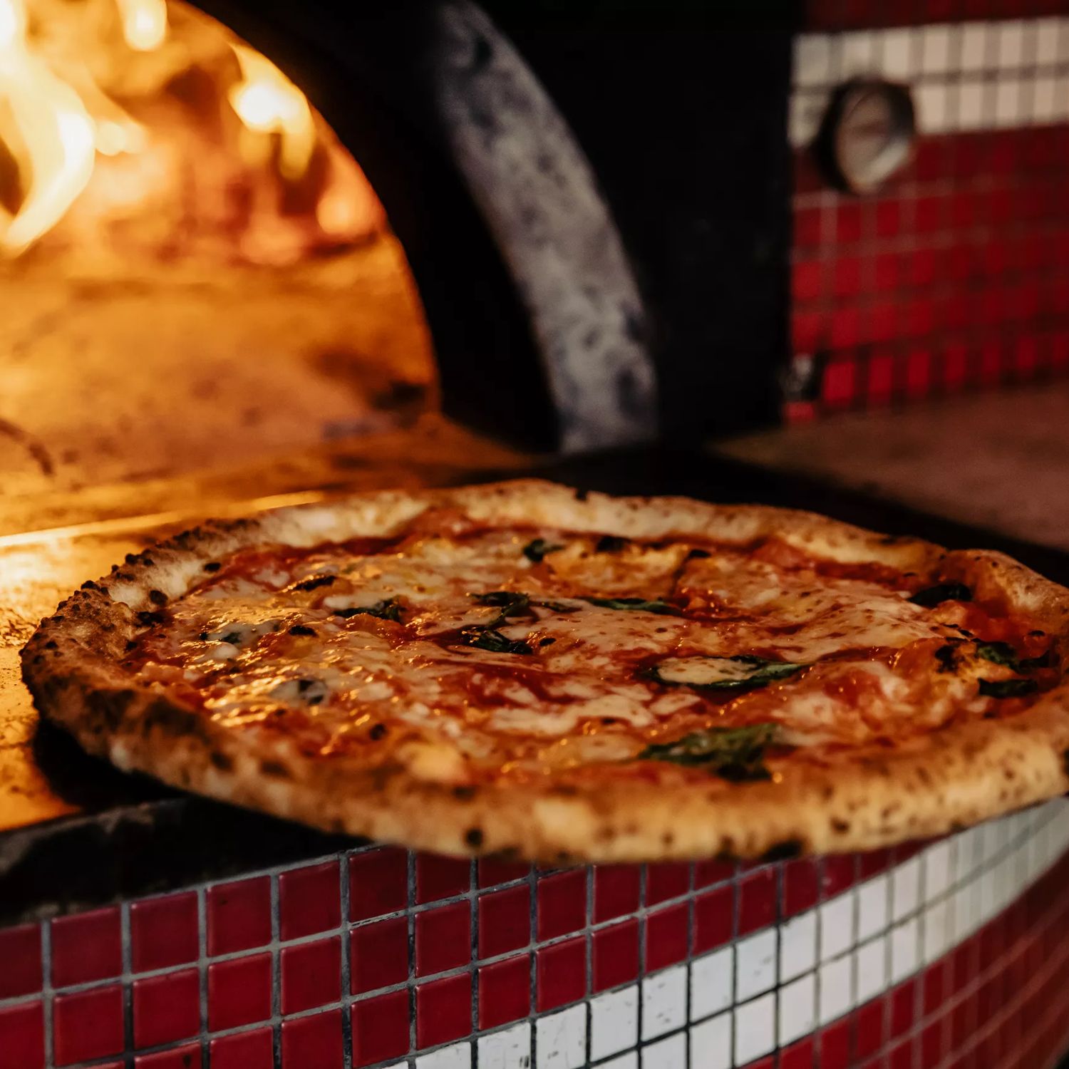 A pizza at Pizza Pomodoro going into a fire oven.