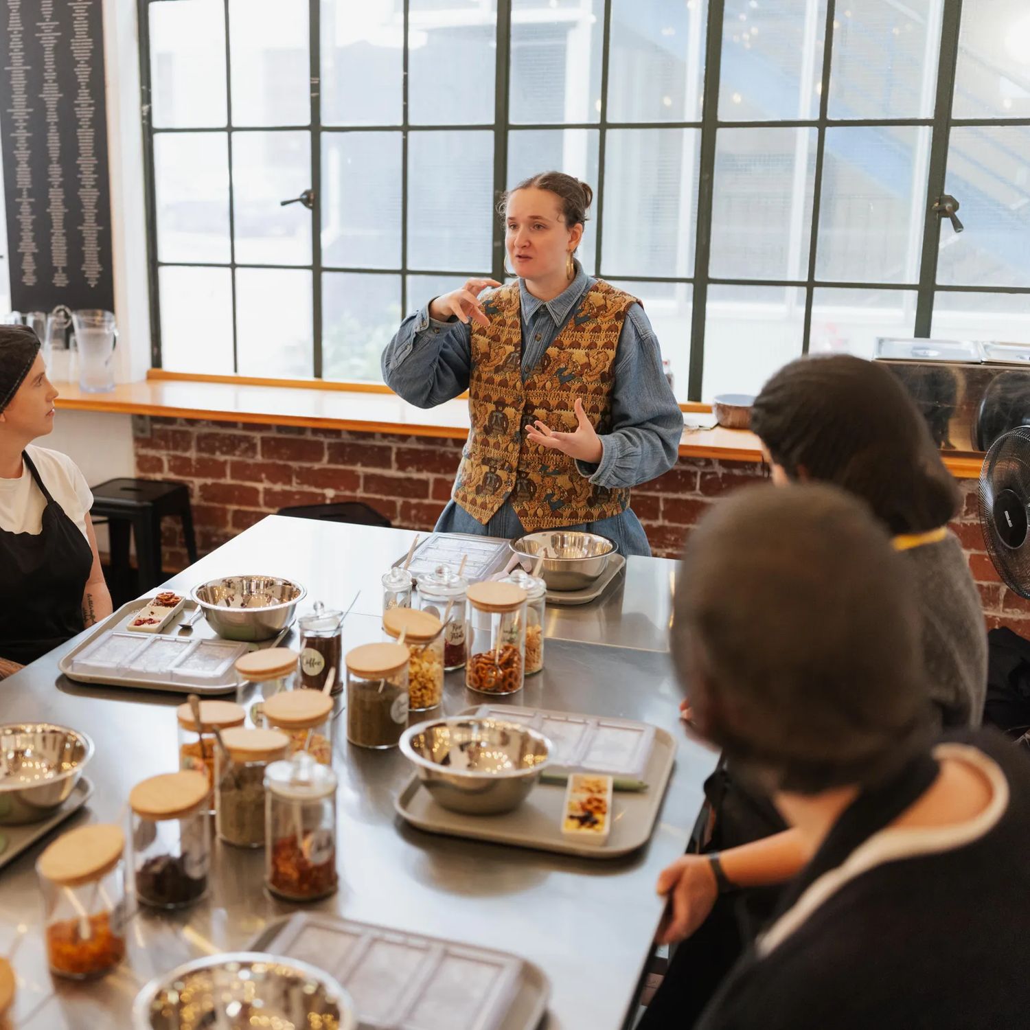 A tour guide demonstrates a part of the Chocolatier Tour at Wellington Chocolate Factory to a group of people listening.